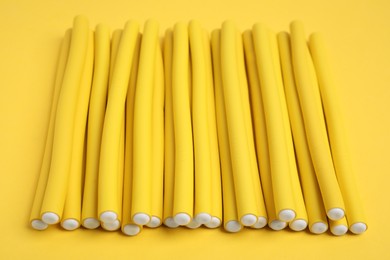 Photo of Curling rods on yellow background. Hair styling tool