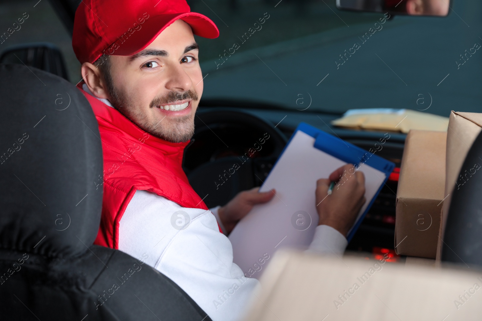 Photo of Deliveryman with clipboard and parcels in car