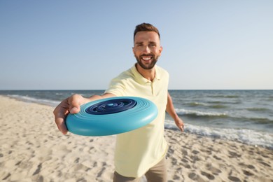 Happy man throwing flying disk at beach, focus on hand