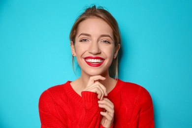 Beautiful young woman in warm sweater on color background