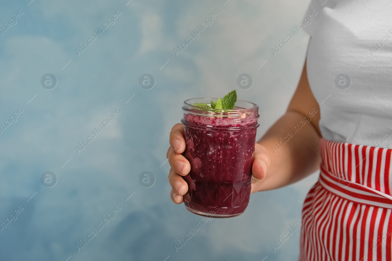 Photo of Woman holding mason jar of delicious acai juice, closeup