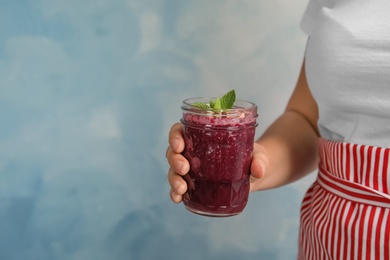 Photo of Woman holding mason jar of delicious acai juice, closeup