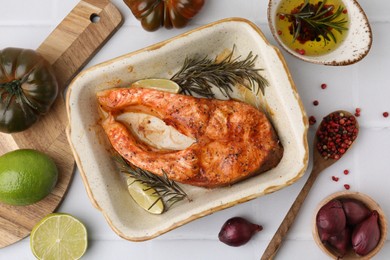 Photo of Freshly cooked fish and other products on white tiled table, flat lay