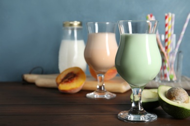 Glasses with delicious milk shakes and ingredients on table