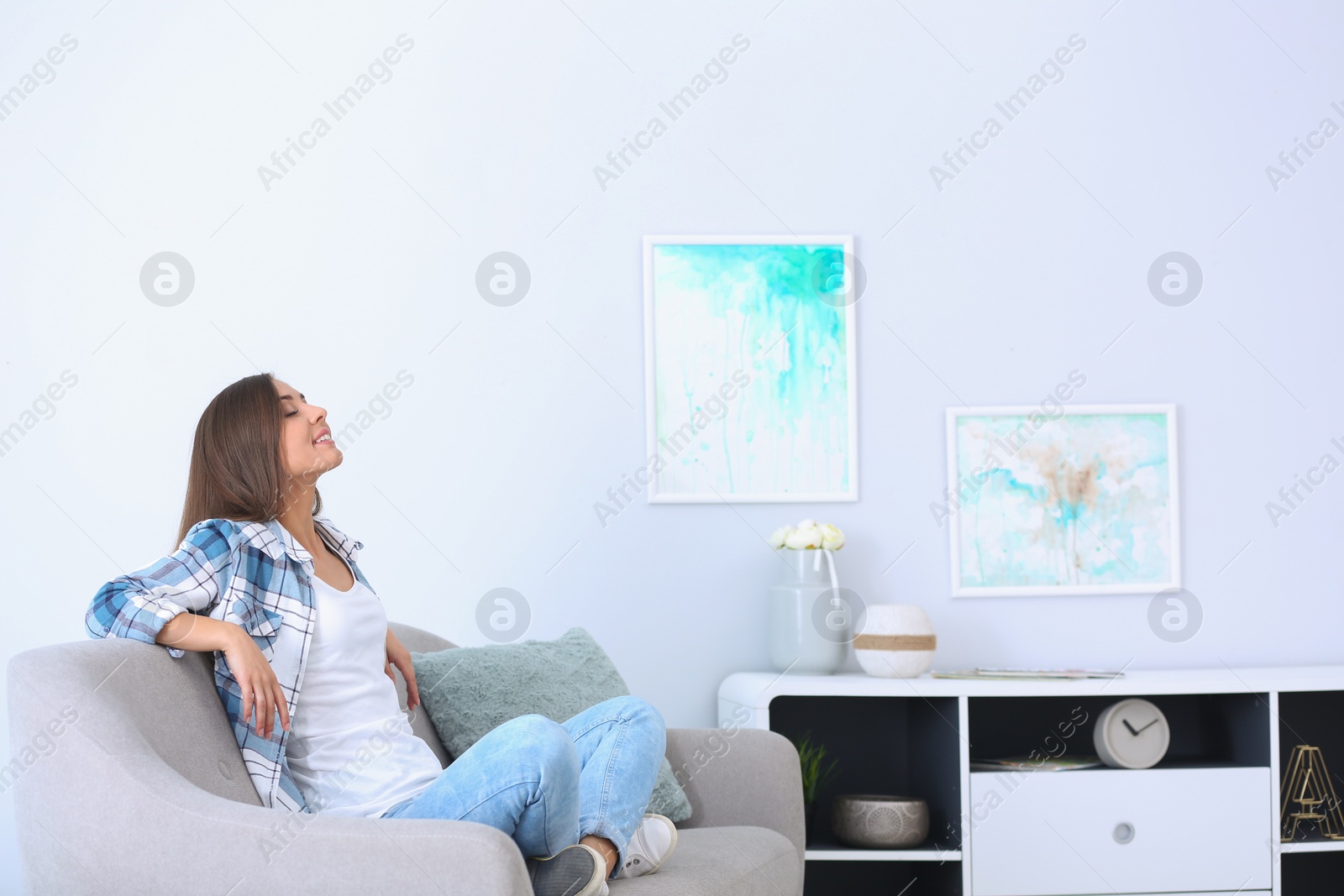 Photo of Young woman relaxing under air conditioner at home