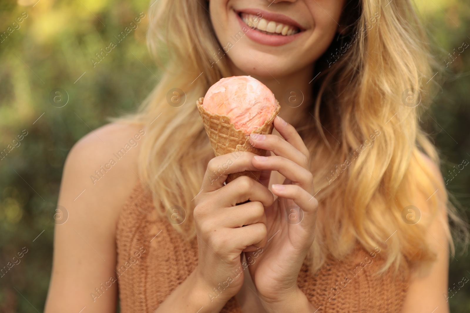 Photo of Young woman with delicious ice cream in waffle cone outdoors, closeup