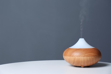 Photo of Aroma oil diffuser lamp on table against gray background. Space for text