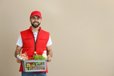 Photo of Man holding basket with fresh products on color background, space for text. Food delivery service