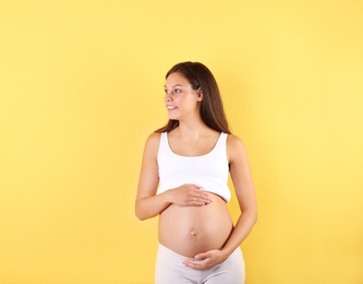 Happy pregnant woman posing on color background