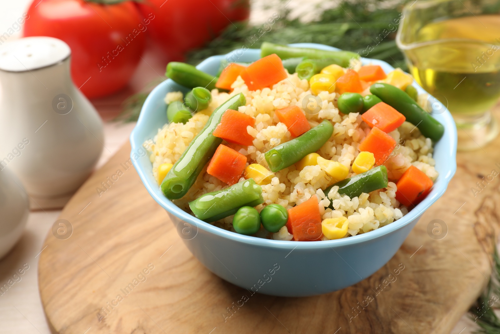 Photo of Delicious bulgur with vegetables in bowl on table, closeup