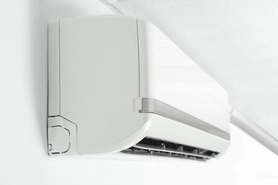 Modern air conditioner on white wall indoors, closeup