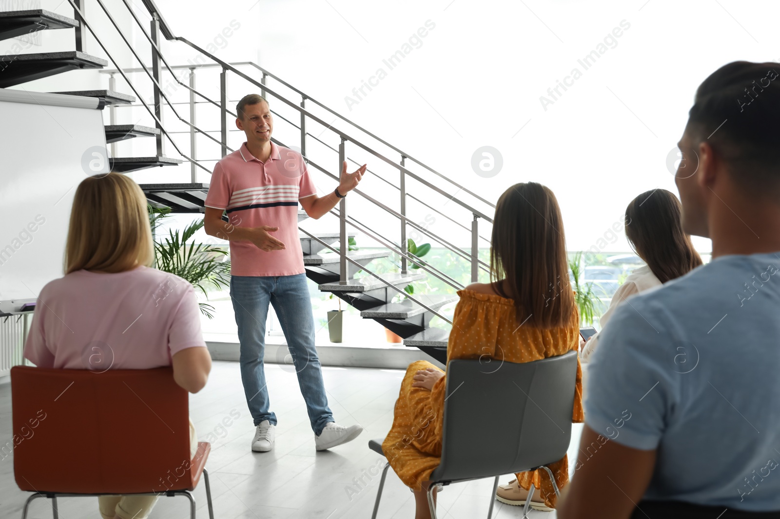 Photo of Male lecturer in casual clothes talking to audience indoors