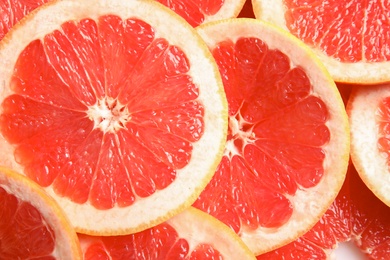 Many sliced fresh grapefruits as background, top view