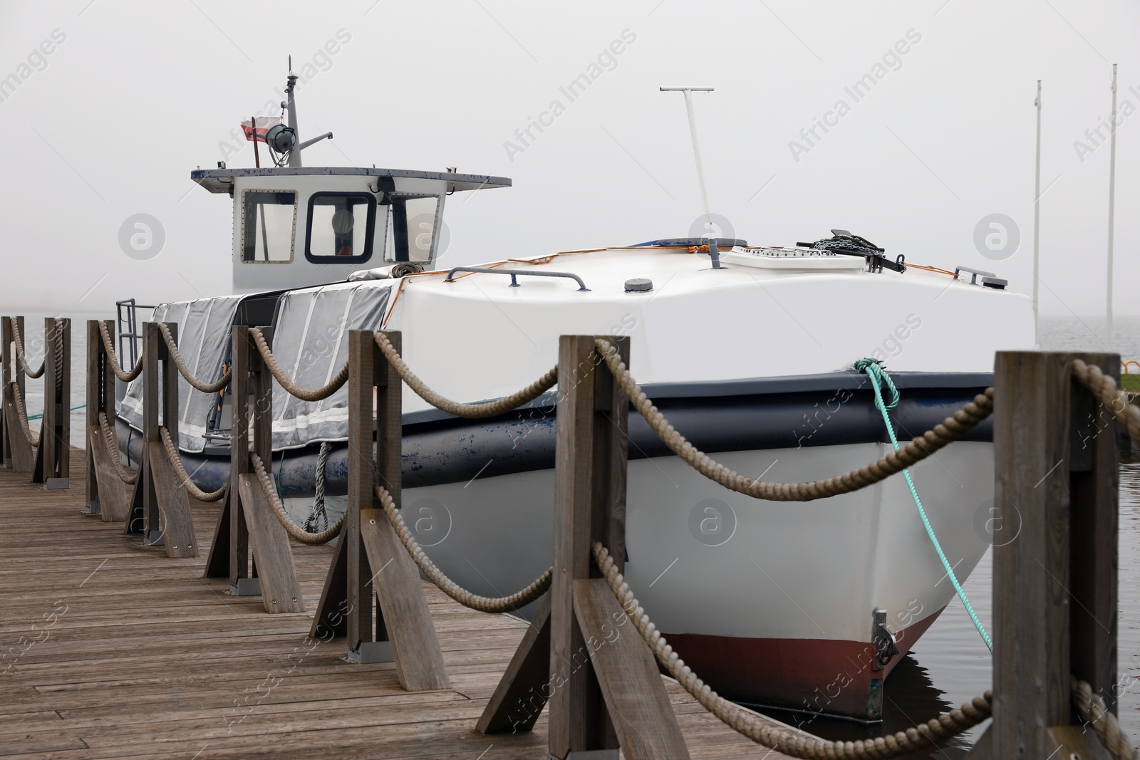 Photo of Picturesque view of moored boat behind pier fence