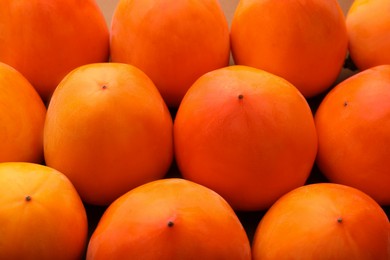 Photo of Pile of delicious ripe juicy persimmons as background, closeup