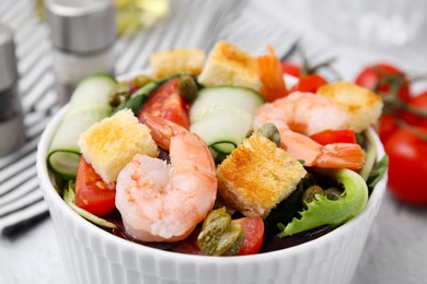 Photo of Tasty salad with croutons, tomato and capers on table, closeup