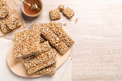 Photo of Delicious sweet kozinaki bars and honey on wooden table, flat lay. Space for text