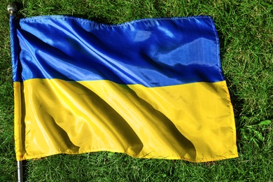 Photo of National flag of Ukraine on green grass, top view