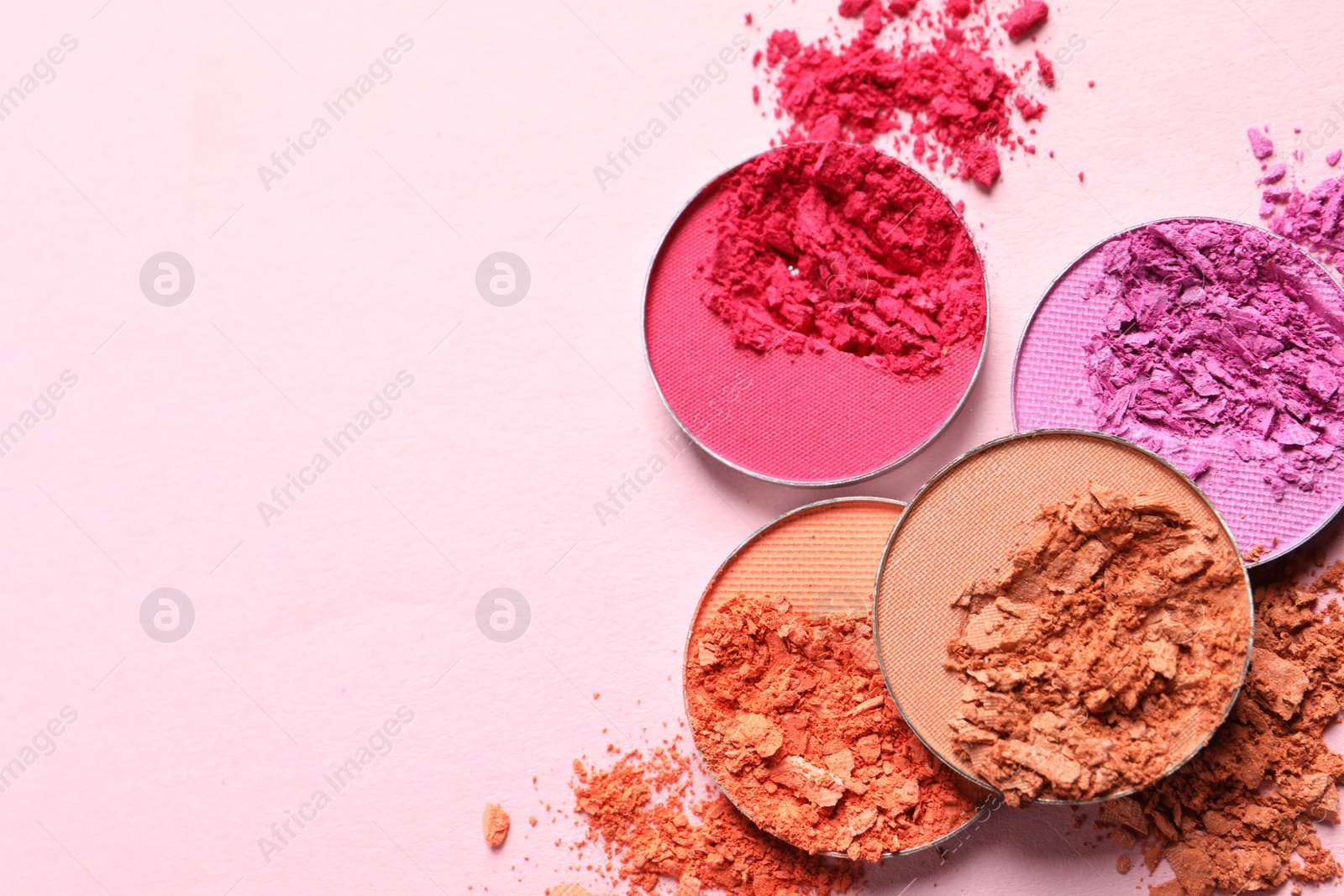 Photo of Different crushed eye shadows on pink background, flat lay. Space for text