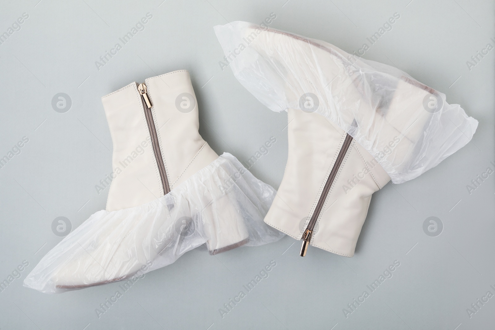 Photo of Women's boots in shoe covers on grey background, top view