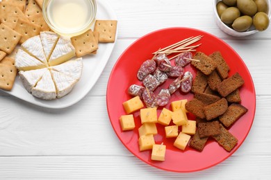 Toothpick appetizers. Pieces of sausage, cheese and croutons on white wooden table, flat lay