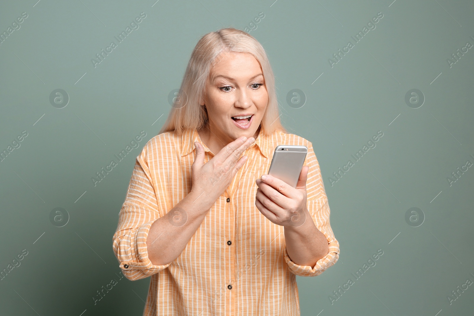 Photo of Mature woman using mobile phone on color background