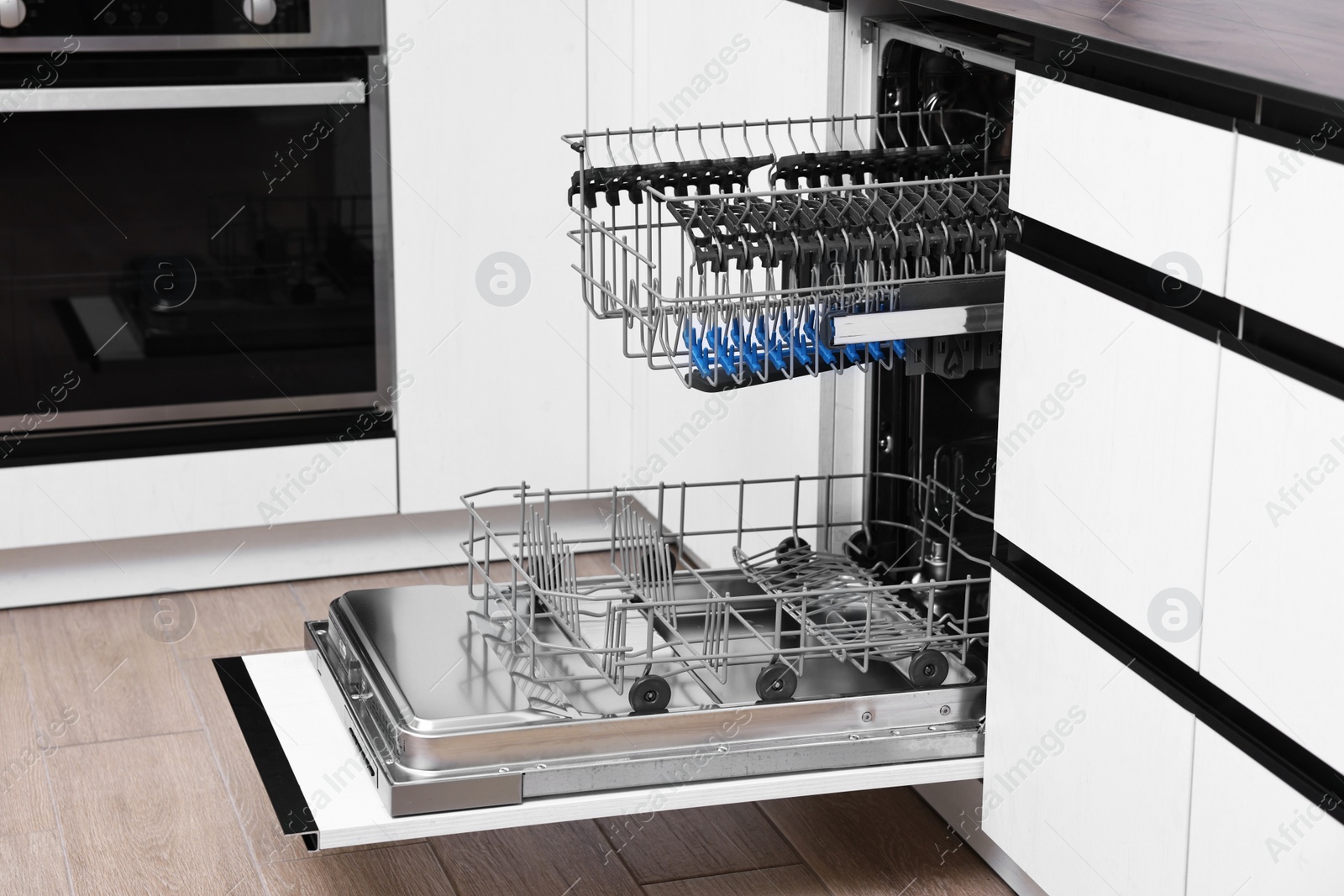 Photo of Open clean empty dishwasher in kitchen. Home appliance