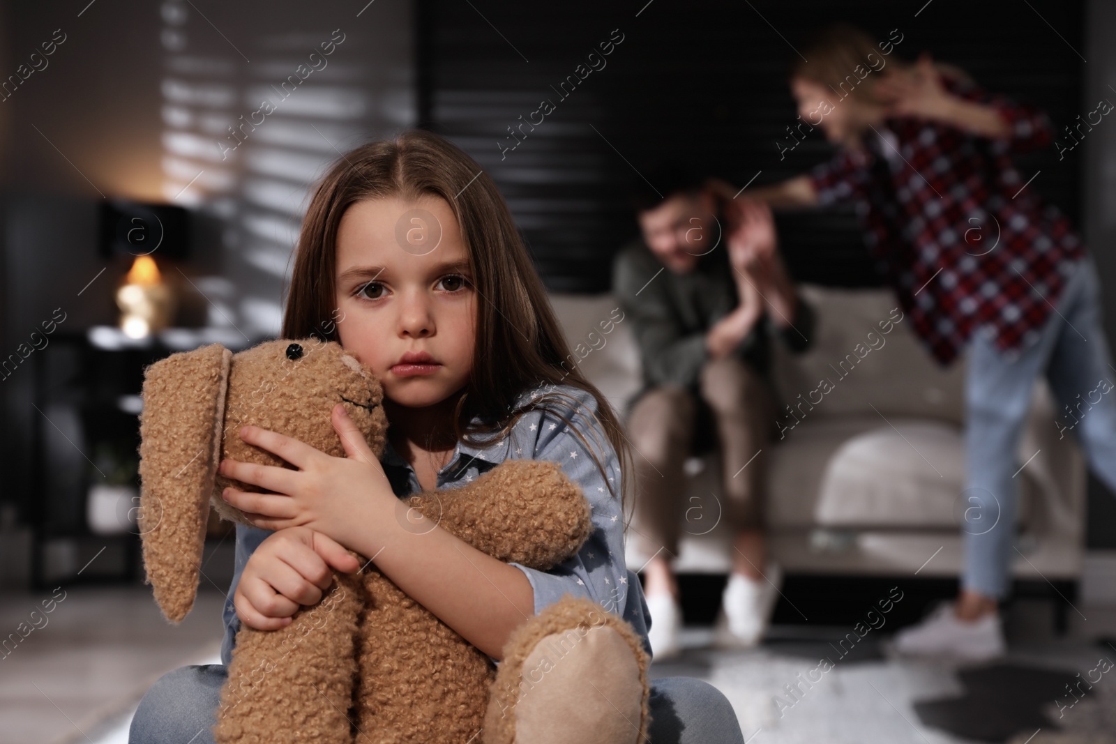 Photo of Couple fighting at home, focus on their unhappy little daughter. Domestic violence