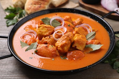 Delicious chicken curry in pan on wooden table, closeup