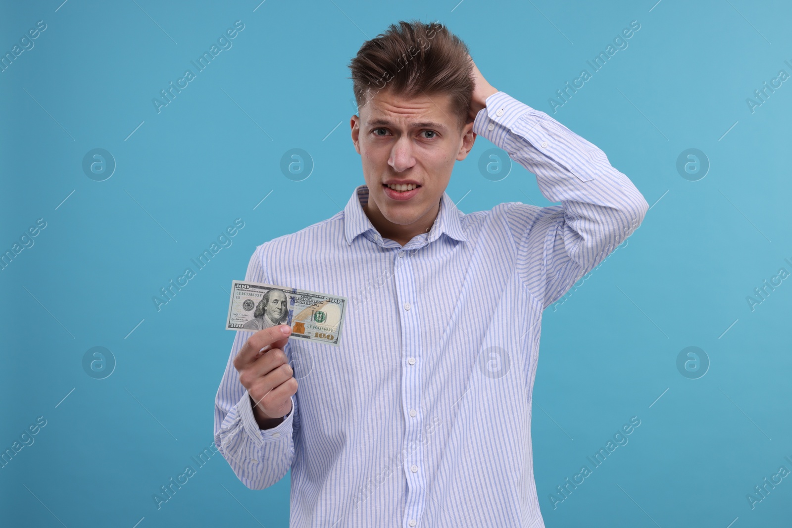 Photo of Upset man with dollar banknote on light blue background