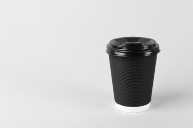 Black paper cup with plastic lid on light background, space for text. Coffee to go