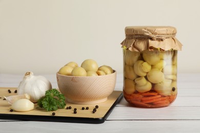 Tasty pickled mushrooms and spices on white wooden table