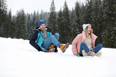 Happy friends sliding on sleds outdoors. Winter vacation