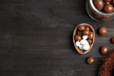 Photo of Half of tasty chocolate egg and candies on black wooden table, flat lay. Space for text