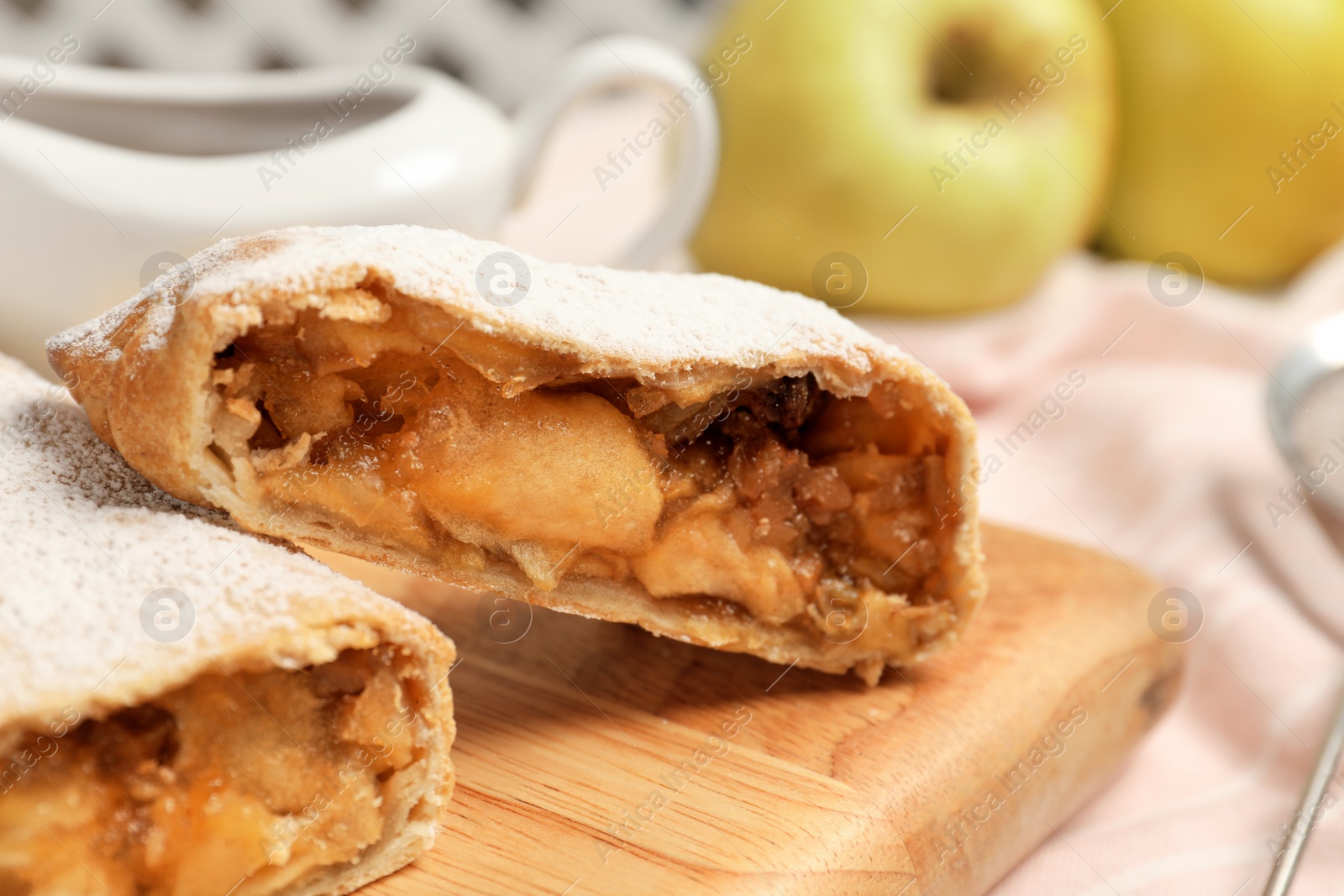 Photo of Delicious strudel with apples and nuts on wooden board, closeup