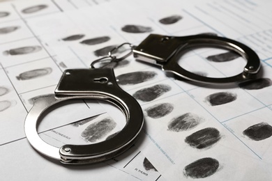 Photo of Police handcuffs and criminal fingerprints card, closeup