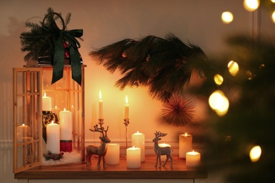 Wooden decorative Christmas lantern and burning candles on table indoors