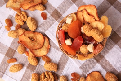 Mixed dried fruits and nuts on checkered tablecloth, flat lay