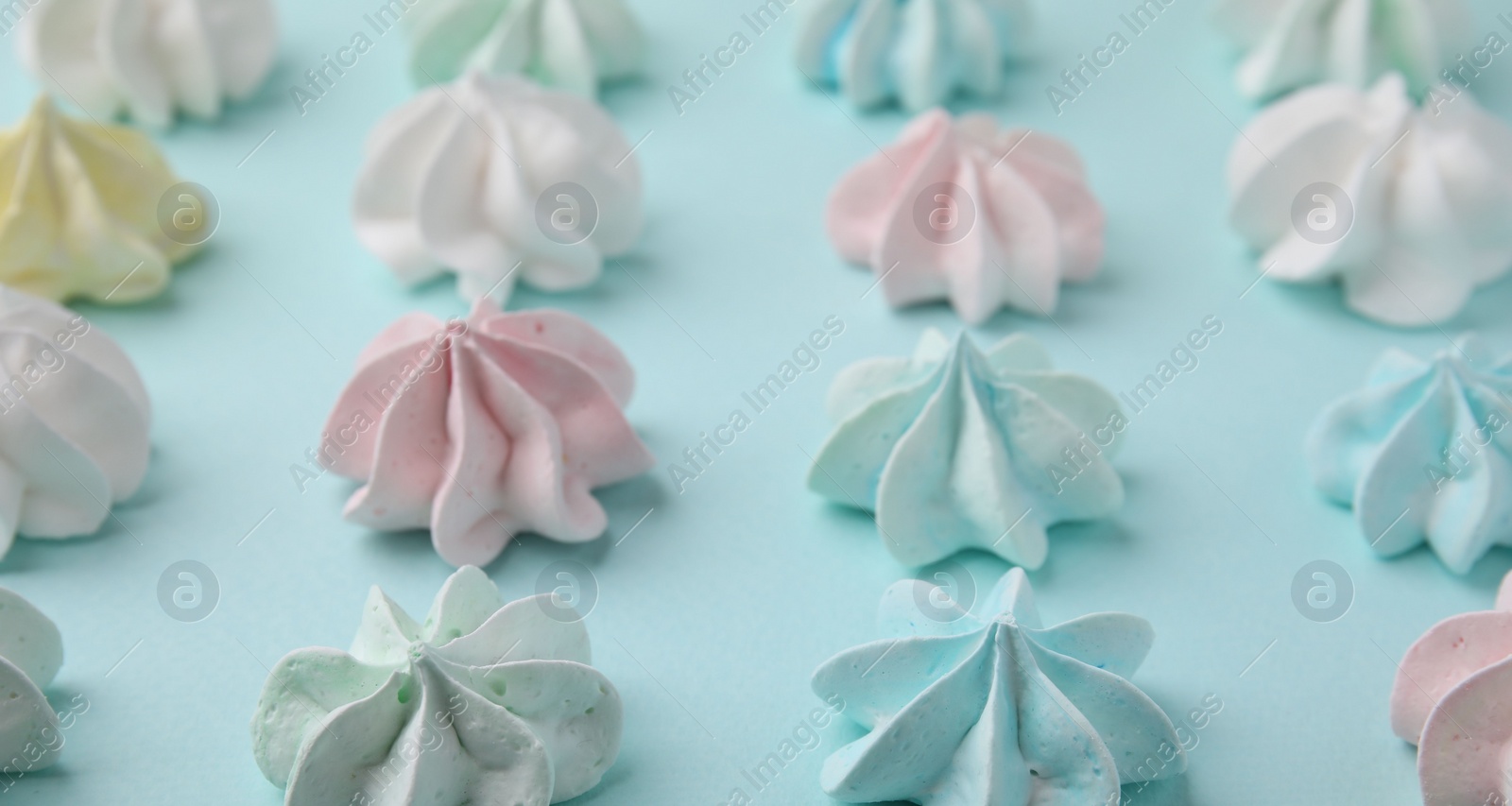 Photo of Delicious meringue cookies on light blue background, closeup