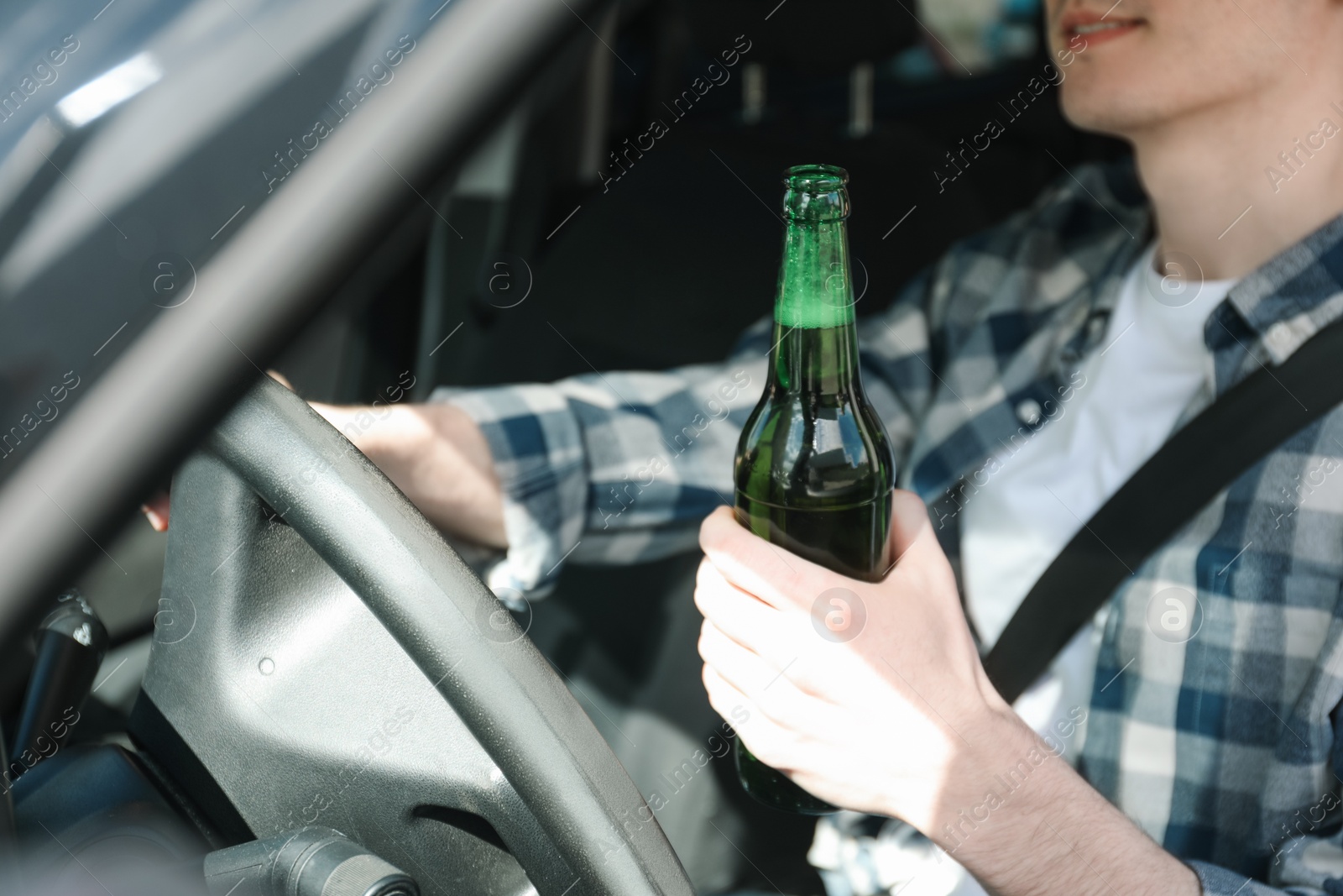 Photo of Man with bottle of beer driving car, closeup. Don't drink and drive concept