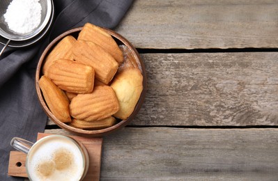 Photo of Tasty madeleine cookies in bowl on wooden table, flat lay. Space for text