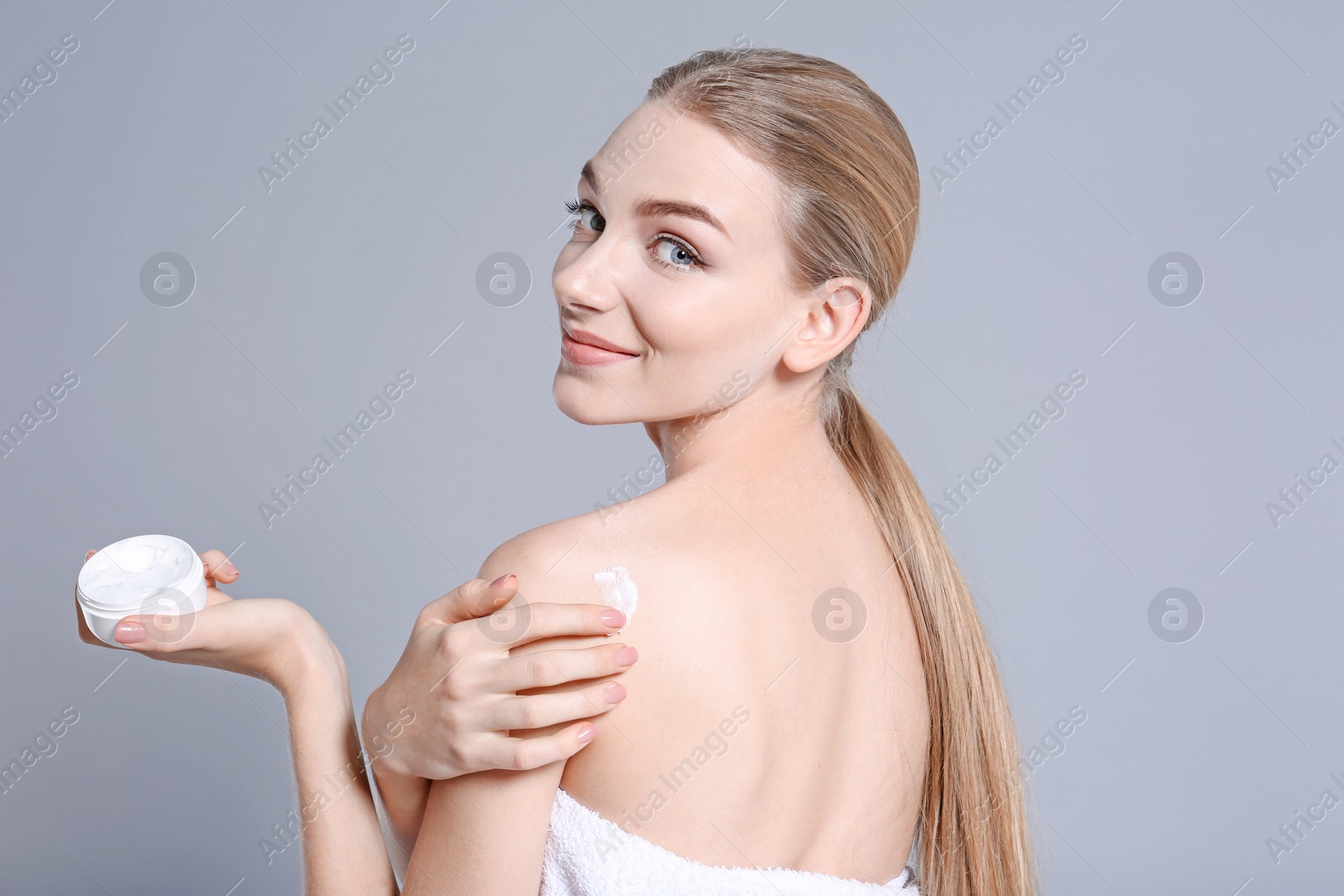 Photo of Young woman with jar of body cream on color background
