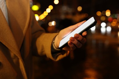 Photo of Woman with smartphone on night city street, closeup