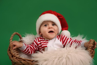 Cute baby in wicker basket on green background. Christmas celebration