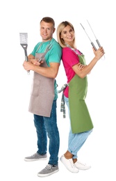 Happy couple with barbecue utensils on white background