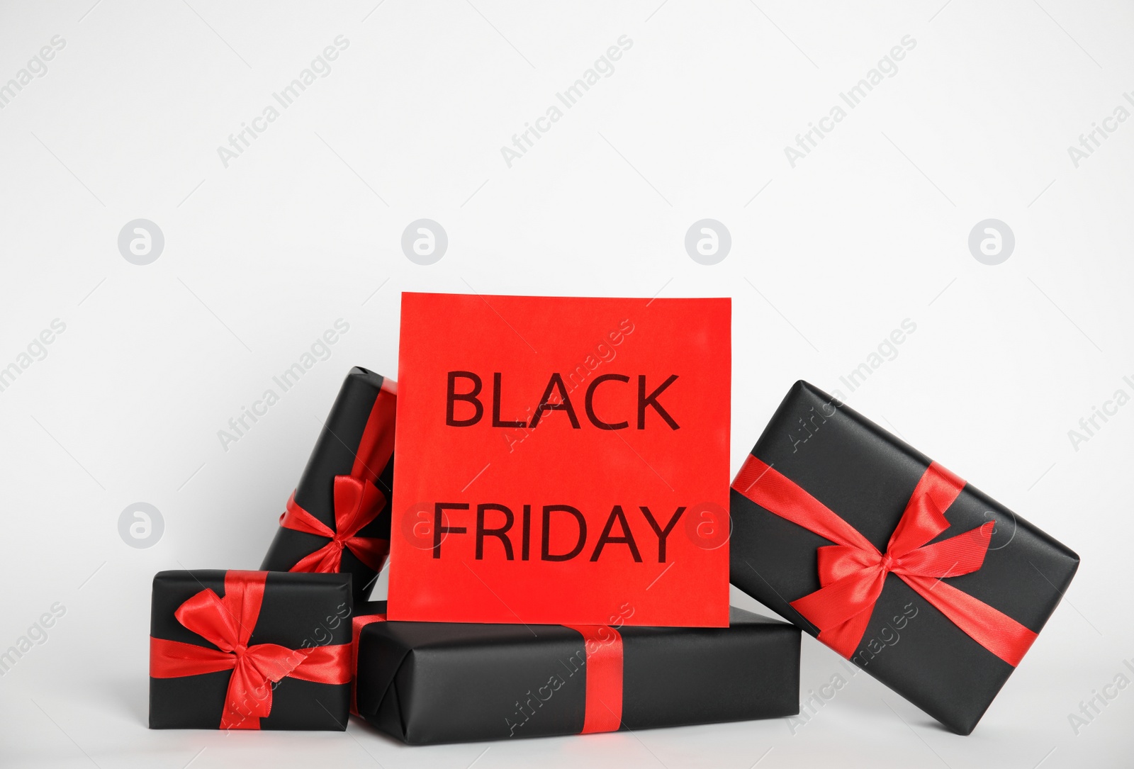 Photo of Many gift boxes and sheet of paper with words Black Friday on white background