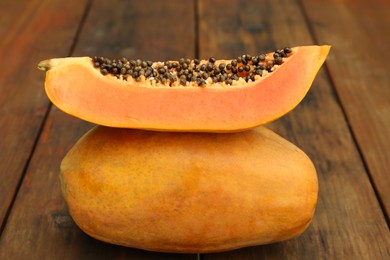 Tasty whole and half papaya fruits on wooden table, closeup