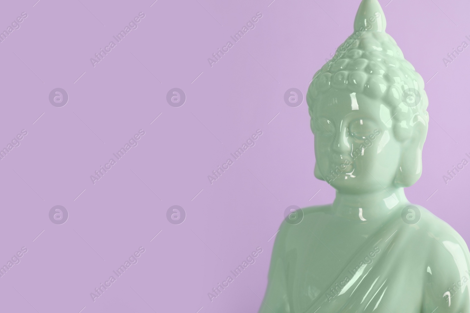 Photo of Beautiful ceramic Buddha sculpture on violet background. Space for text