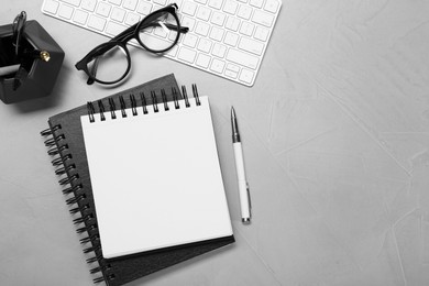 Photo of Flat lay composition with notebooks, keyboard and glasses on light grey table