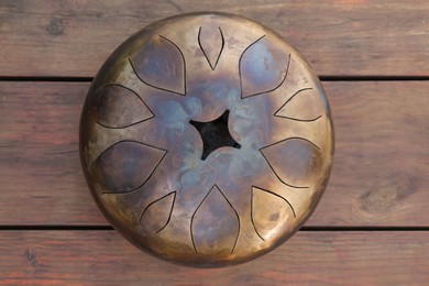 Steel tongue drum on wooden table, top view. Percussion musical instrument